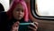 pretty modern little girl with pink hair is riding train and watching cartoons by smartphone