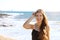 Pretty modern sporty woman with sunglasses on her head looking happy smiling at camera on the beach