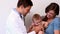 Pretty mother holding baby boy while pediatrician listens to his chest