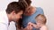 Pretty mother holding baby boy while pediatrician listens to his chest