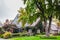 Pretty neighborhood house with wooden shingles and  bird feeders and picket fence and nice landscaping in traditional neighborhood