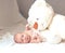 Pretty newborn baby girl with a big soft toy lying on the blanket.