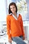 Pretty office worker smiling in orange pullover