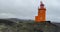 Pretty orange Hopsnes Lighthouse near Grindavik, Iceland on the Reykjanes Peninsula. Side panning establishing shot