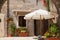 A pretty patio with umbrella ,colorful flowers and wooden doors, old part of town, Italy