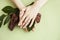 Pretty perfect woman hands with white manicure and green leaf on colorful background with wood, spa cosmetic concept