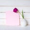 Pretty Pink Blank Card with a Purple Tulip in Gray Vase on a table and against a White Board Wall Background with room or space fo