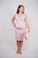 Pretty plump woman in pink dress with patent leather stiletto heels on white background in Studio