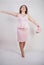 Pretty plump woman in pink dress with patent leather stiletto heels on white background in Studio