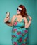 Pretty plus-size fat woman with hollywood smile in fashion sunglasses and colorful clothes does fashion selfie on mint