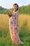 Pretty pregnant woman in dress poses with wild flowers at s