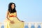 Pretty pregnant woman over sky in yellow dress