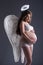 Pretty pregnant woman posing in angel costume