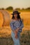 Pretty pregnant woman sexily posing for camera in nature, pregnant beauty with long black hair in straw hat