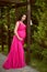 Pretty pregnant woman wearing in pink dress at green park