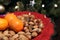 Pretty red Christmas plate with traditional festive almonds, hazelnuts and Brazil nuts, and three satsumas,with a Christmas tree