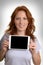 Pretty red-haired woman holding mini tablet pc before body