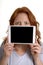 Pretty red-haired woman holding mini tablet pc before face