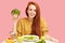 Pretty redhead caucasian woman sitting at table with healthy food and broccoli