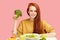 Pretty redhead caucasian woman sitting at table with healthy food and broccoli