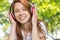 Pretty redhead listening to music in the park