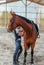 pretty rider with her helmet and her vest tightening the girth of her mare