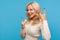 Pretty satisfied blond woman in knitted sweater showing rock and roll gesture with toothy smile on face, positivity, happy of