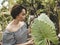 A pretty short haired asian lady wearing an off shoulder top checks a Gabi or Taro leaf at a garden