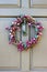 Pretty simple purple wreath with vines and leaves and fruit hangs on a door knocker of a painted door