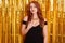 Pretty slim caucasian girl posing against sparkle tinsel on background during new year party. Stunning red haired woman wears