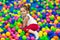 Pretty small girl plays in children zone in amusement mall, lies on colourful balls, smiles positively, looks at camera. Little ch