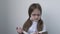 Pretty small serious schoolgirl in white school blouse and glasses reading a book. Portrait of little student girl