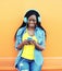 Pretty smiling african woman with headphones listens to music over orange