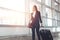 Pretty smiling female flight attendant carrying baggage going to airplane in the airport