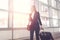 Pretty smiling female flight attendant carrying baggage going to airplane in the airport