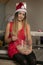 Pretty smiling girl in Christmas clothing sitting on the table and preparing cake for baked goods