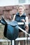 Pretty smiling teenage girl equestrian cleans black Leather Horse Saddle