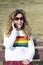 Pretty smiling teenager girl talking by phone. Happy curly young girl wear rainbow sweater