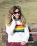 Pretty smiling teenager girl talking by phone. Happy curly young girl wear rainbow sweater