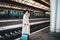 Pretty smiling woman at the railway station. Positive tourist lady in a hat and coat who is standing at the railway station with a