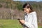 Pretty smiling young woman breathes fresh air in the park listening to music on headphones and holding a smartphone