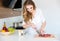 Pretty smiling young woman cutting meat on the kitchen