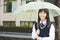 Pretty student girl holding umbrella in the rain