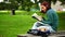 Pretty student sitting on bench reading a book listening to music