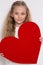 Pretty stunning little girl little princess, holding a red heart in his hands and standing on a white background