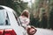 Pretty and style woman traveler sitting in car and looking from window on wild road