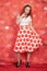 Pretty stylish pin up girl in white shirt and red polka dot vintage skirt standing on red hearts background