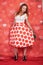 Pretty stylish pin up girl in white shirt and red polka dot vintage skirt standing on red hearts background