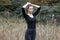 Pretty stylish young woman in black trendy shirt in fashionable jeans posing in a field among dry grass. Attractive girl