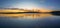 Pretty sunrise waterscape panorama with low colourful clouds